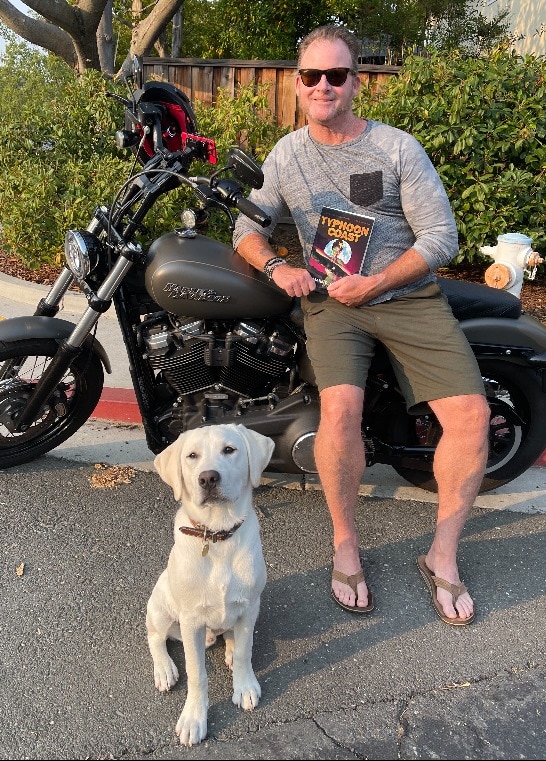A white dog accompanies a man sitting next to a motorcycle on the Typhoon Coast, in this historical fiction tale set during the USMC era.